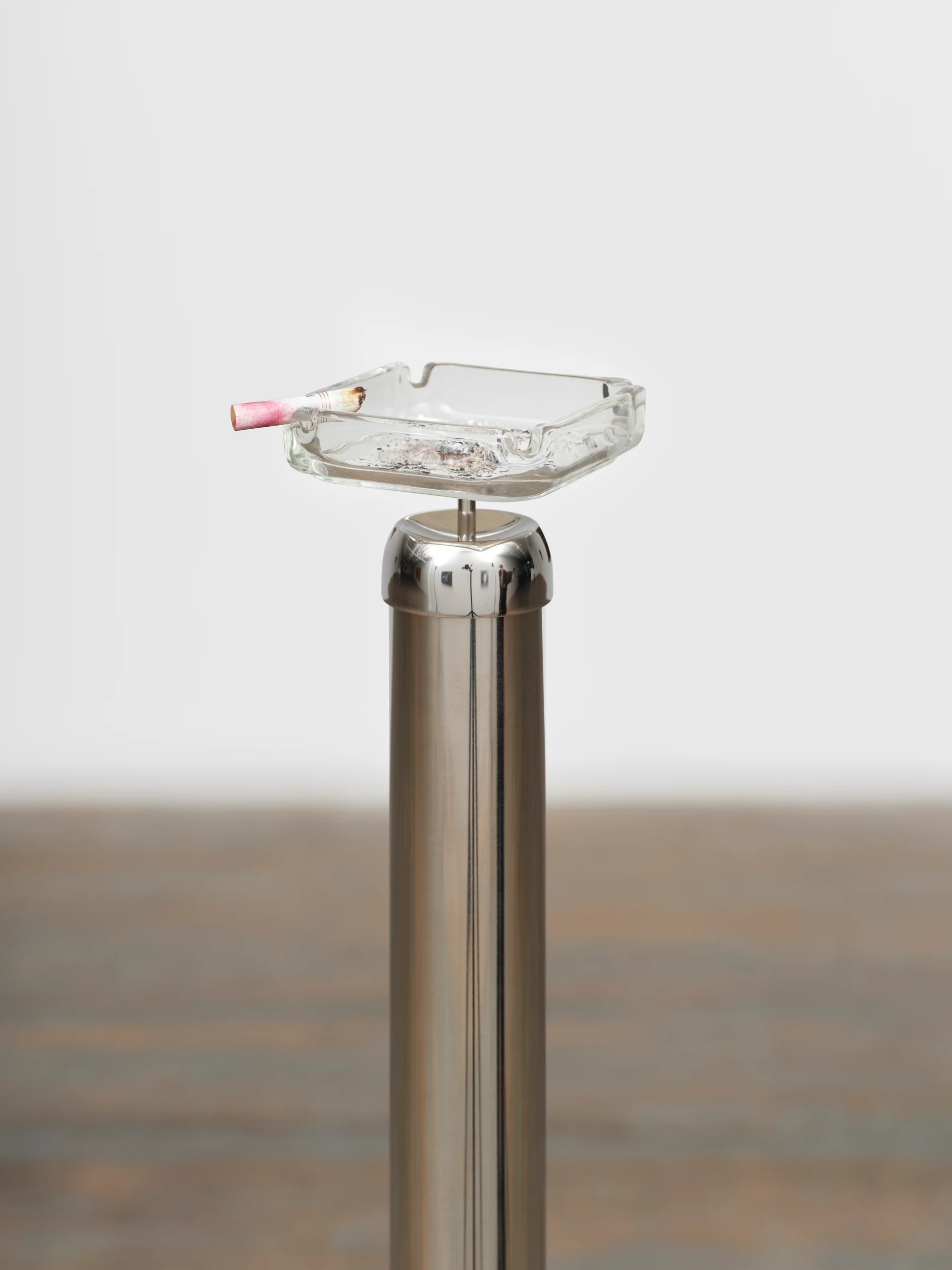 Andrew J. Greene, Timeless Symbols (Carlyle ashtray), 2026, Stainless steel stanchions, display motors, vintage ashtray, cigarette , 50 1/2 x 5 in, 128.3 x 12.7 cm